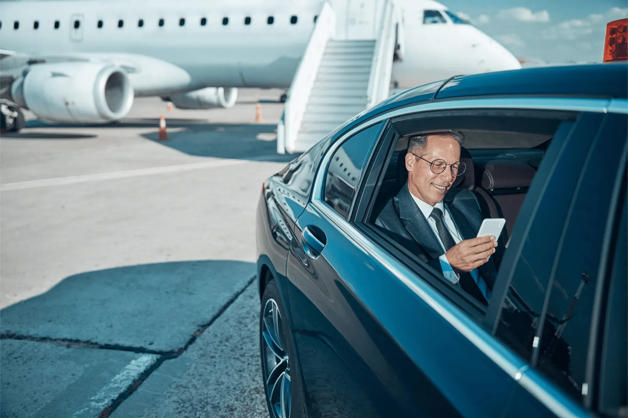 Business traveller in a car on the airport apron next to a plane