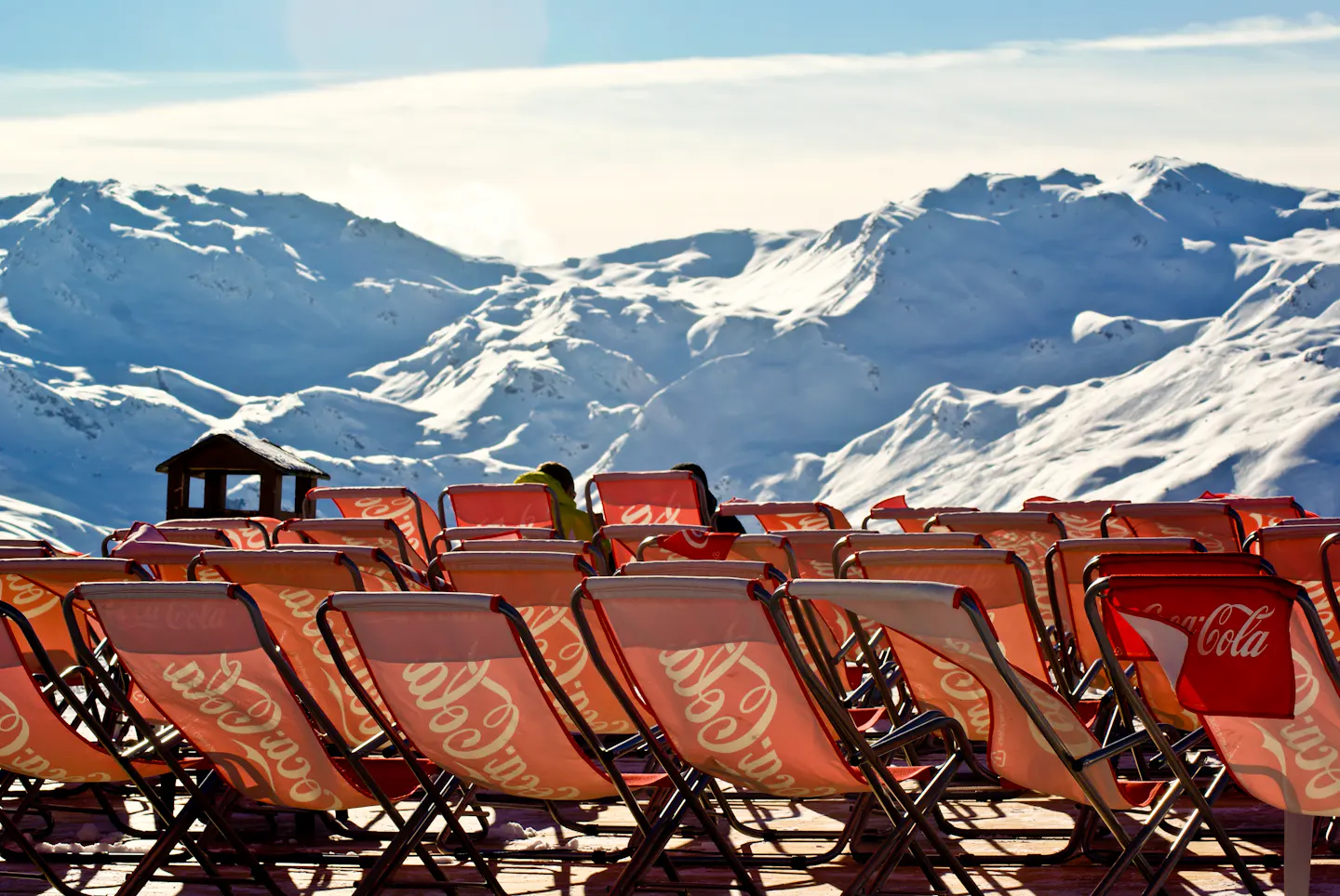 Red deckchairs facing the snowy peaks of the Three Valleys