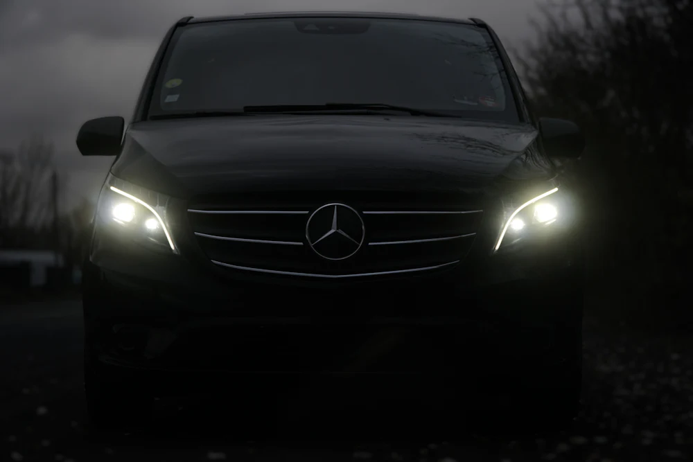 Black Mercedes V-Class van with headlights on