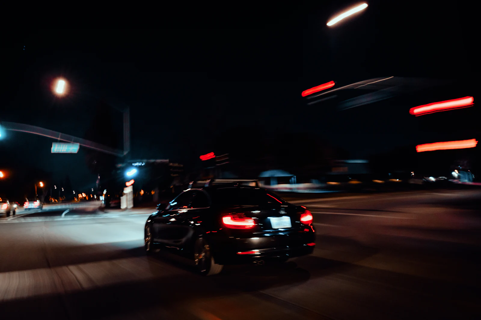 Dark car driving through city streets at night