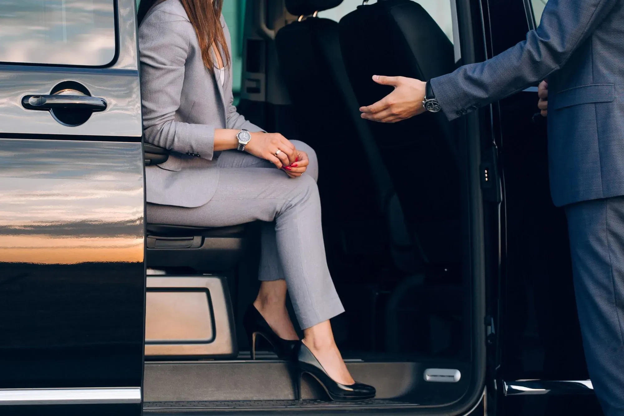 Chauffeur helping a passenger into a black van