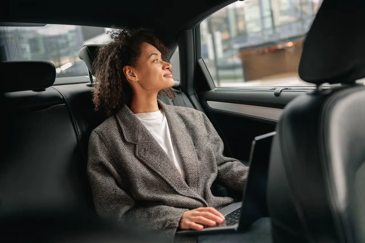 Passenger with a laptop in the back seat of a car