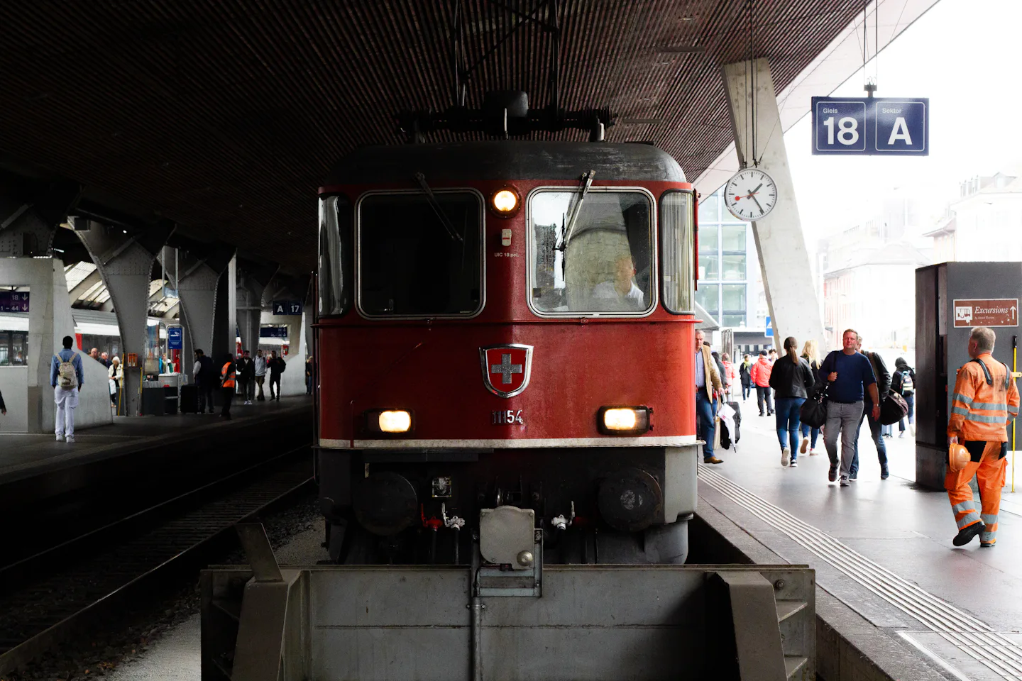 Red Swiss train at a station platform with travellers